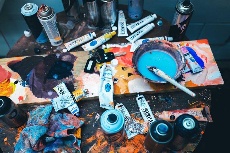 Banner 1500x1000 caleb salomons 486024 unsplash paint tubes, spray cans, paint brushes and other art material scattered over a table
