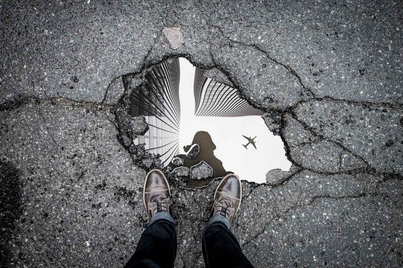 Banner 1500x1000 marc olivier jodoin 502572 unsplash a puddle reflecting the photographer, skyscrapers and a plane