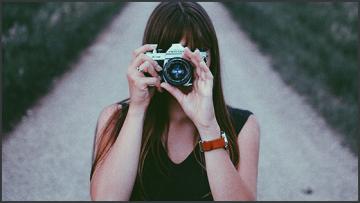 Illustration 560x315 photo 1465450975282 cf81b2f0e693 a girl taking a photo with an analogue camera facing the viewer